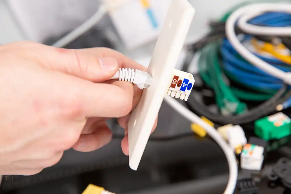 A person is connecting ethernet wires to a wall outlet of a Chicago North Shore home.