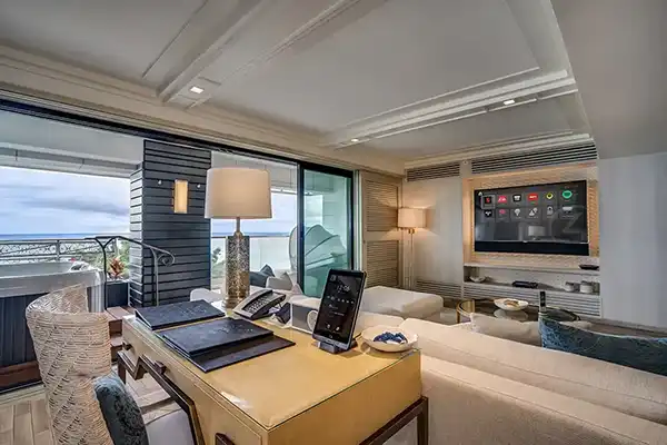 A living room with a tv and a view of the ocean.